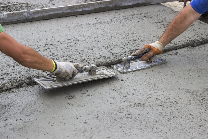 Concrete slab rates-Leveling concrete with trowels, mason hands spreading poured concrete. Selective focus.