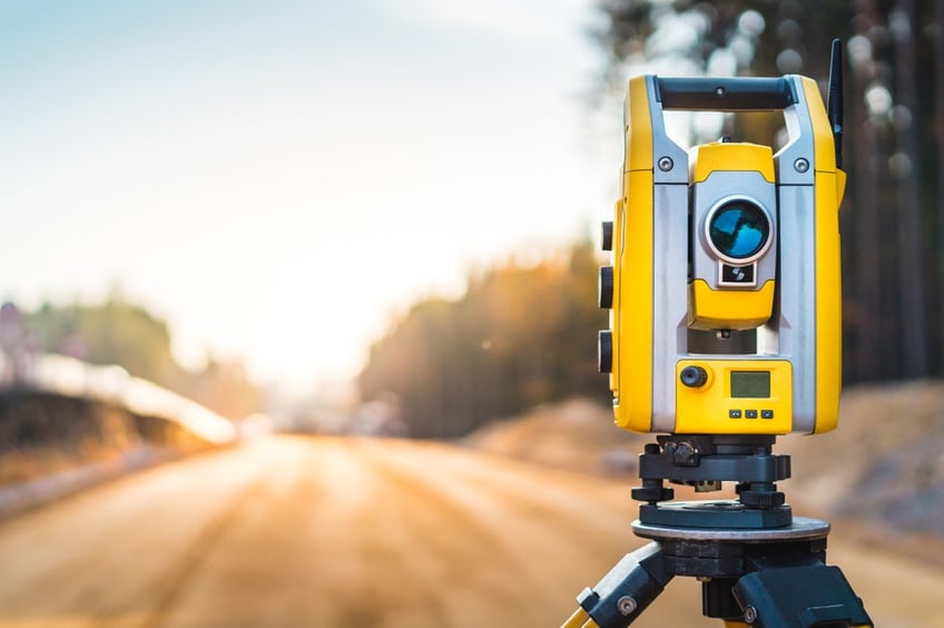 Land surveying costs-Surveyors equipment (theodolite or total positioning station) on the construction site of the road or building with construction machinery background