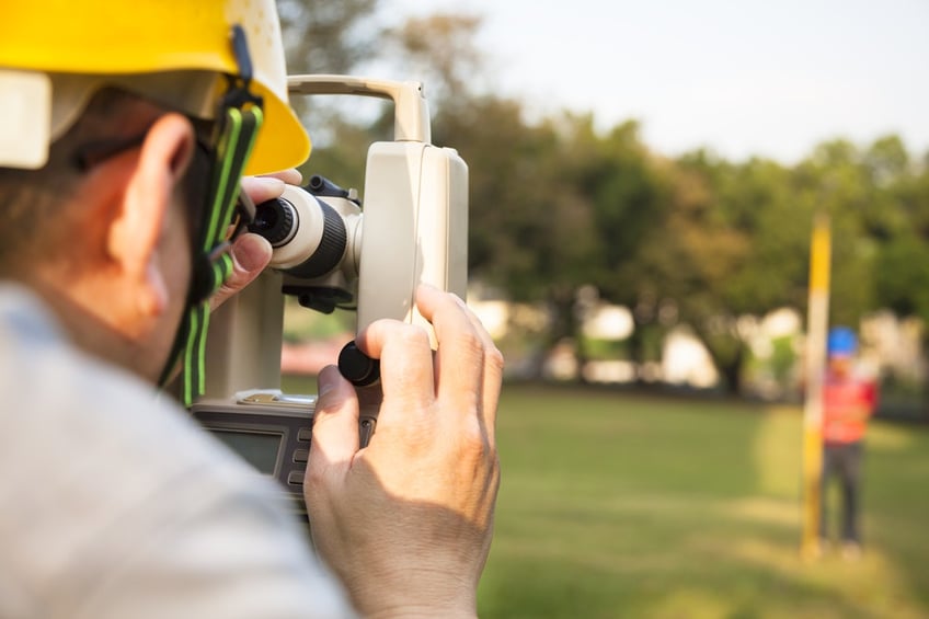 land surveying costs-Surveyor engineer with partner making measure on the field