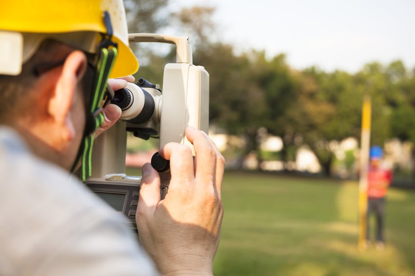 land surveying costs-Surveyor engineer with partner making measure on the field