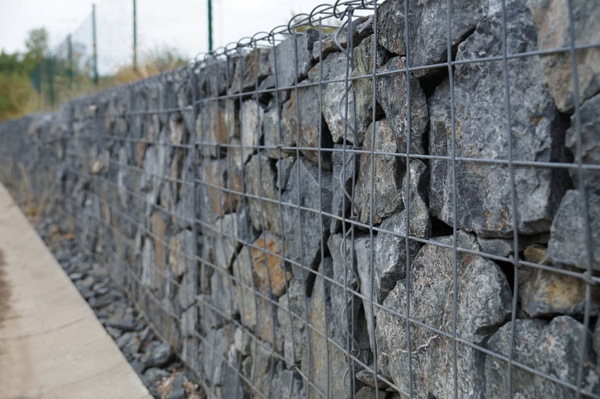 retaining wall costs-Close-up of a retaining wall made of stones. A wall called a gabion.