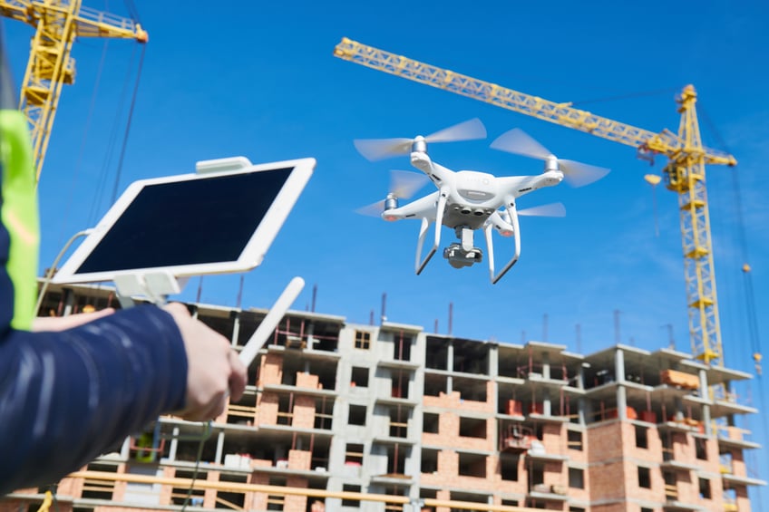 Drone operator using a tablet to fly a drone on a construction site