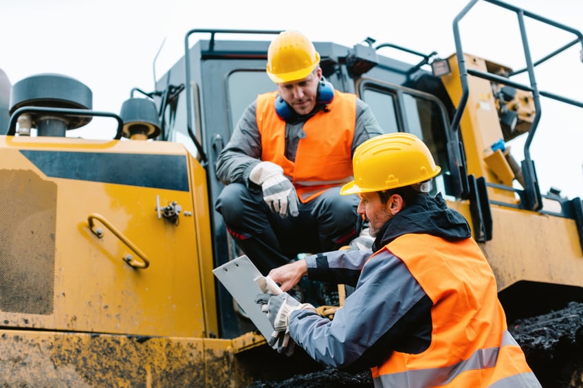 Two contractors on a construction site sitting in a large machine