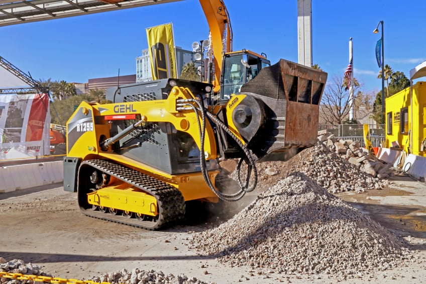 Skid steer with attachment moving aggregate and gravel on a construction site