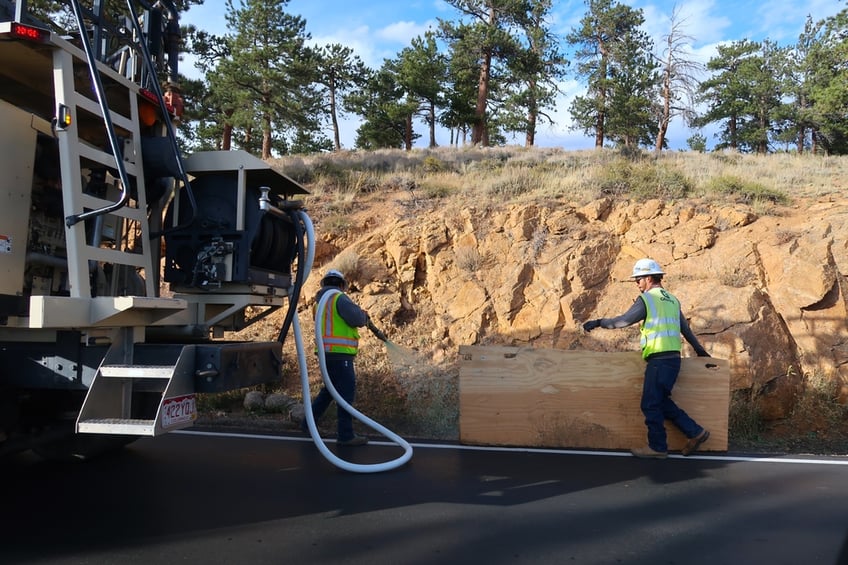Two workers spraying hydroseed on the side of a road
