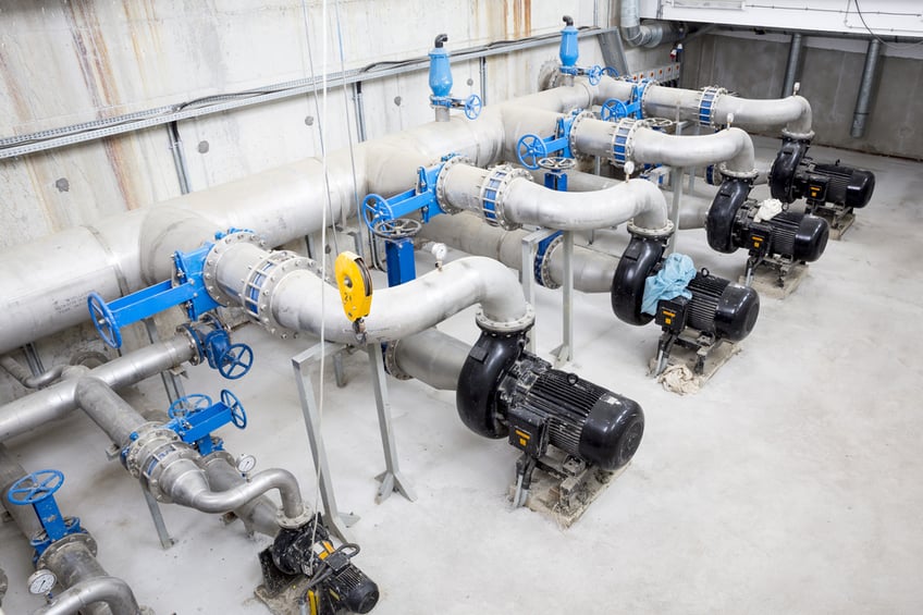 Large industrial water pumps in a row in a factory pumping room