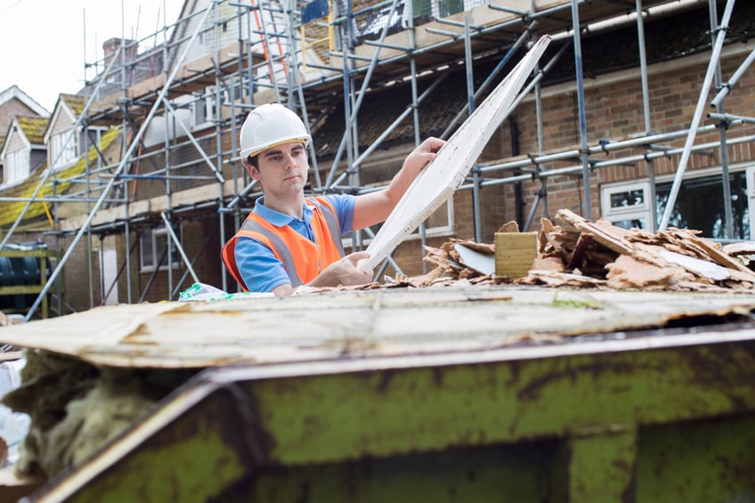Construction worker filling a skip bin with debris